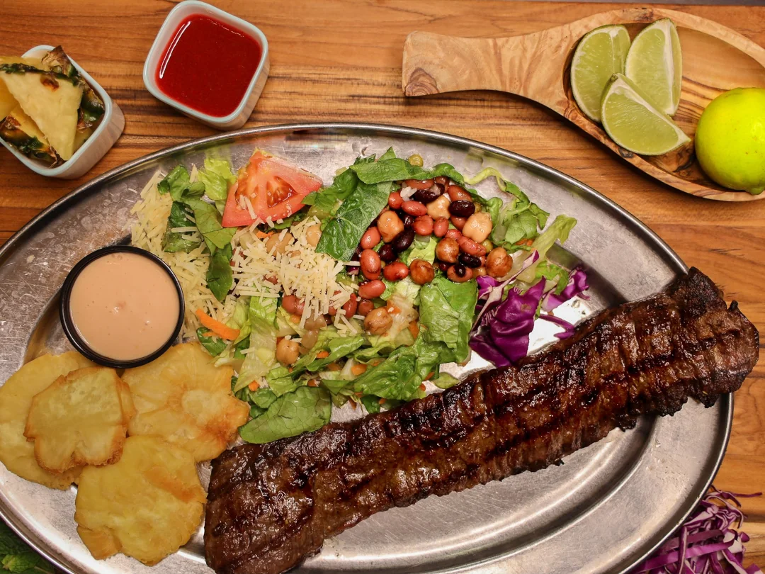 A Steak with side salad and fried plantains from La Parilla Restuarant