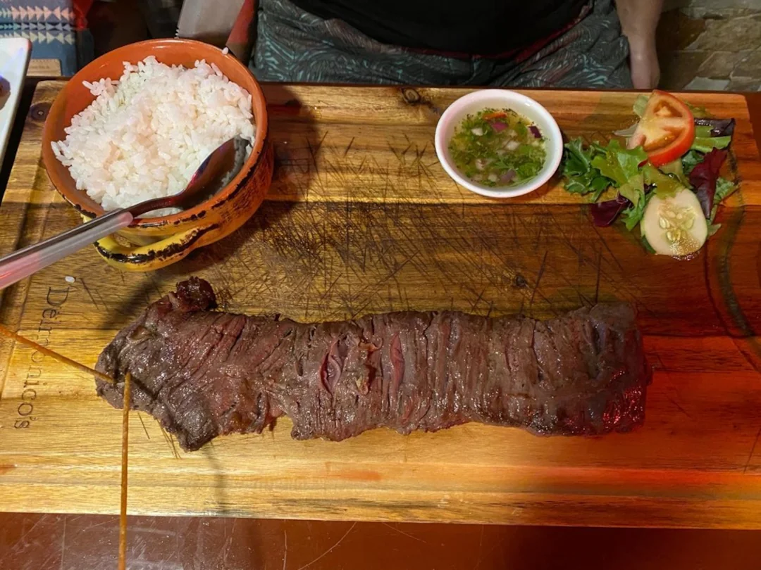 A piece of beef with a side of rice available at tradiciones restaurant.