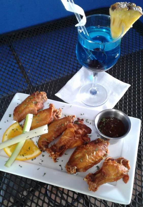 A plate of chicken wings and a blue mixed drink from New York Style sports bar.