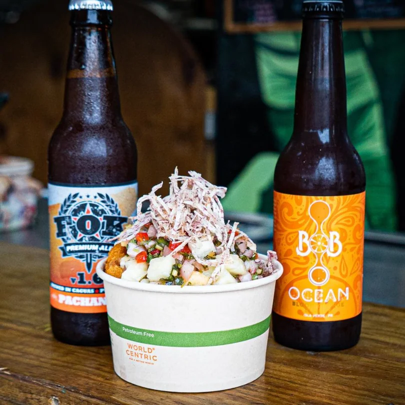 A traditional puerto rican dish served in an ecofriendly container next to two craft beers available at Rellena'o.