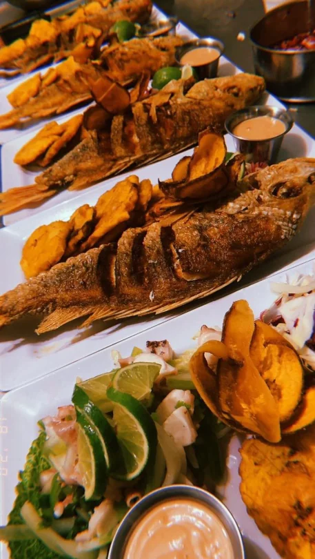 A row of plates with fried fish and chips ready to be served at El Brindis Kiosko En Otro Mundo.