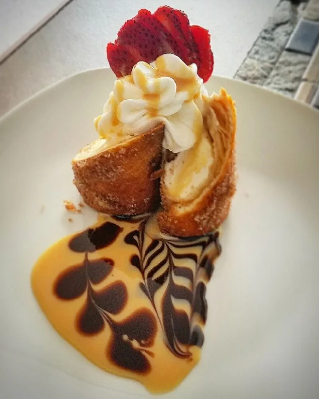 A dessert topped with whipped cream andd strawberries at El Brindis Kiosko En Otro Mundo.