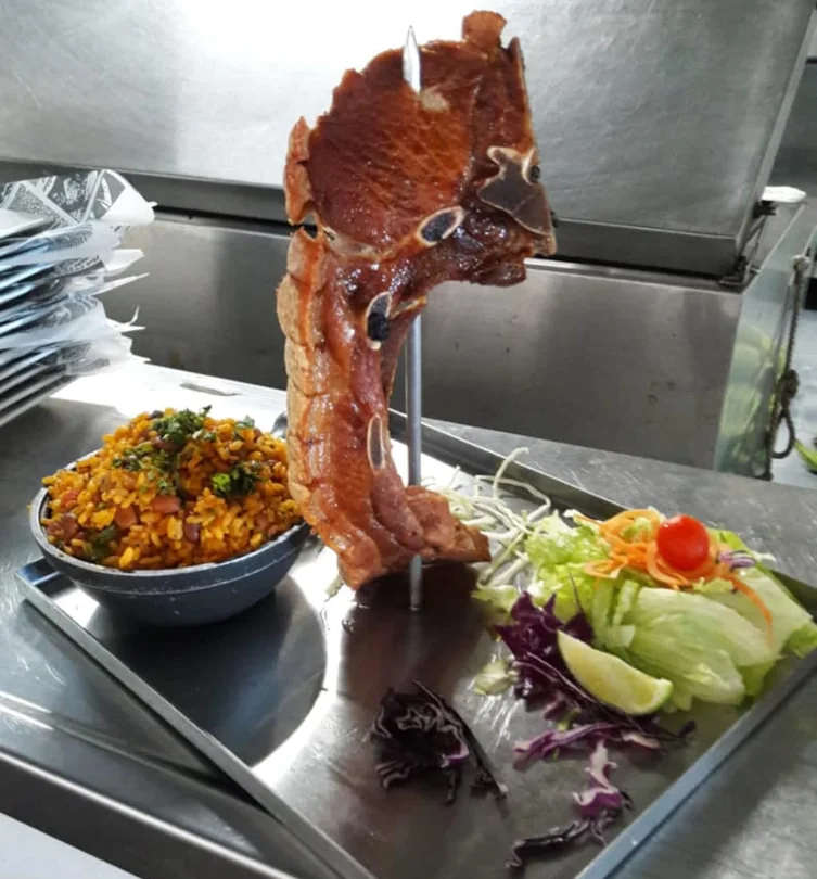 A cooked octopus tentacle displayed next to a bowl of rice and beans and a side salad from A-Fuego Bar and Restaurant.